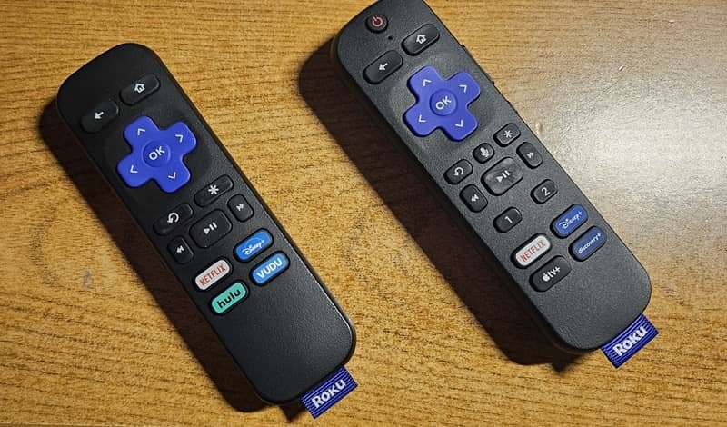 Простой пульт Roku и голосовой пульт Roku, стоящие рядом на столе.