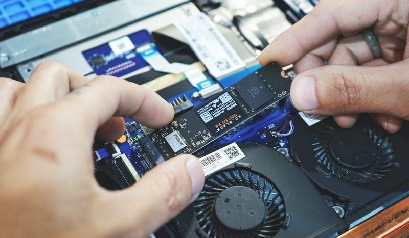 Крупный план двух рук, устанавливающих SSD NVMe в ноутбук