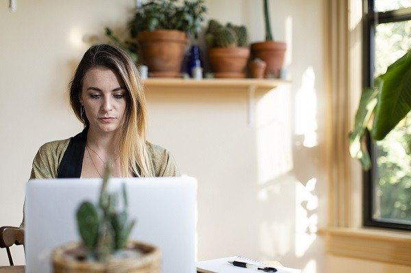Расслабленная женщина работает дома на своем ноутбуке