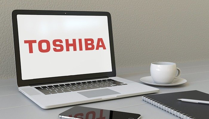 Ноутбук с логотипом корпорации Toshiba на экране. Концептуальная редакционная 3D-рендеринг современного рабочего места